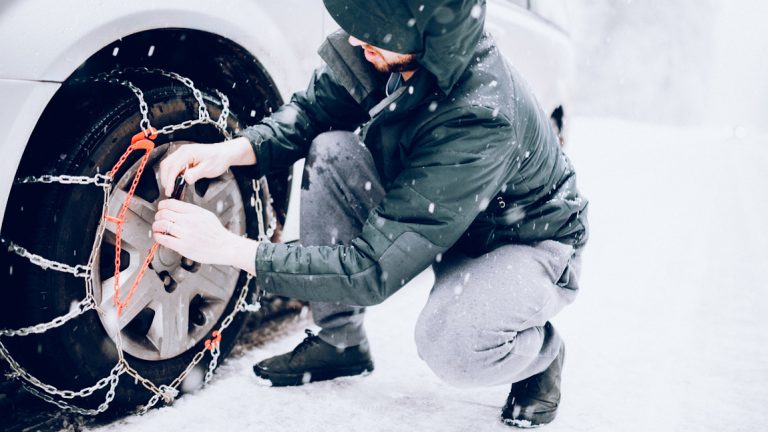 Man Putting Snow Tire Chains On Car